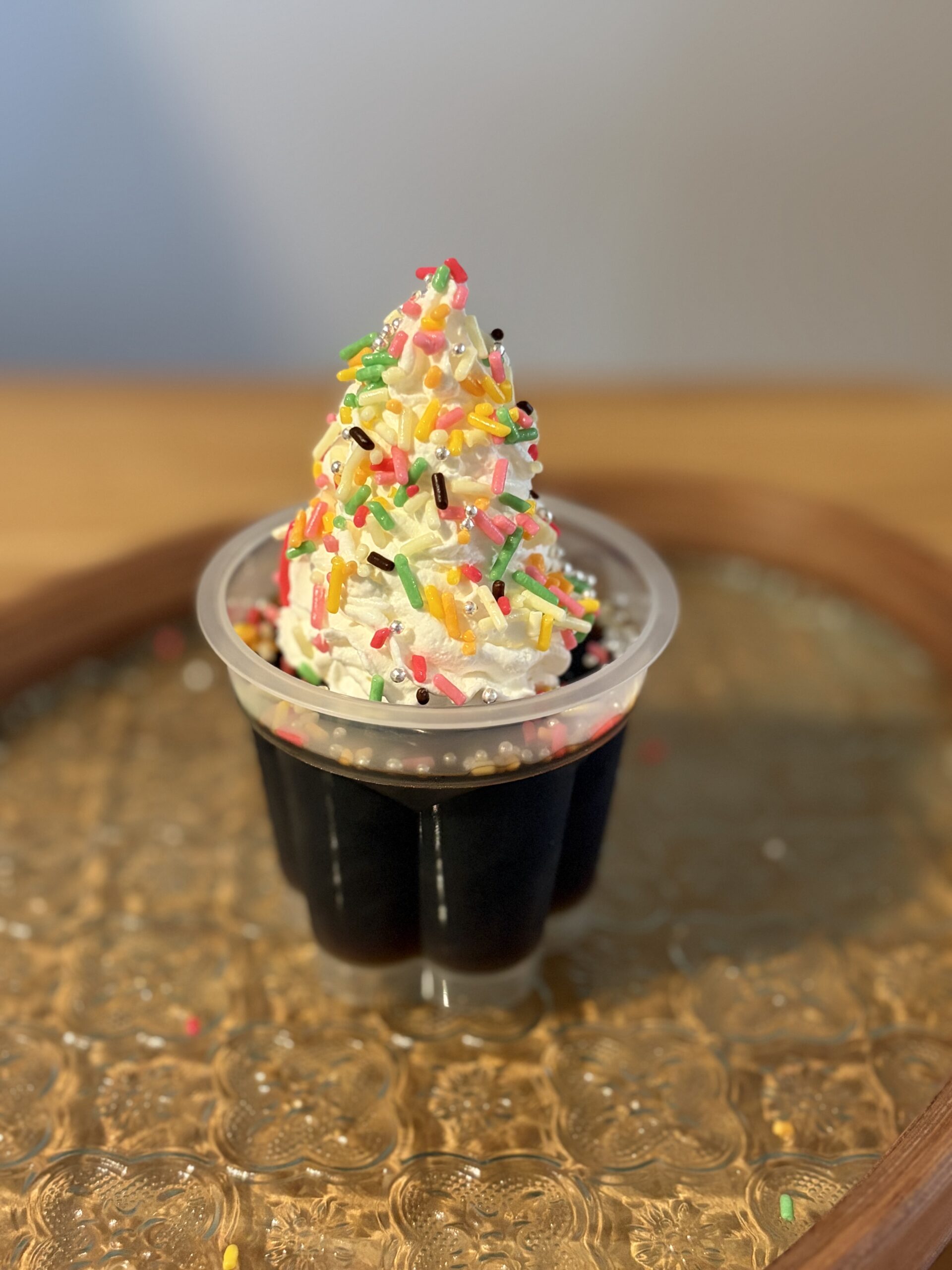 コーヒーゼリーにホイップクリームをのせ、カラースプレーと銀色のアラザンを散らしたデザート