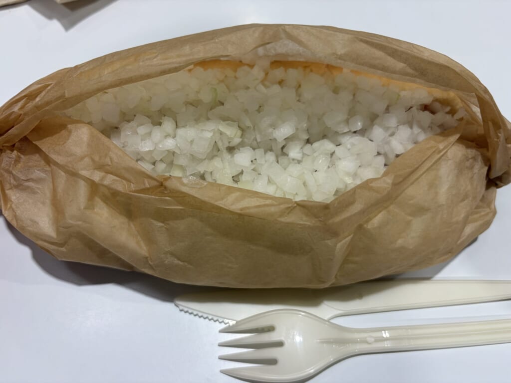 玉ねぎを盛ったホットドッグを紙で包んだところ
